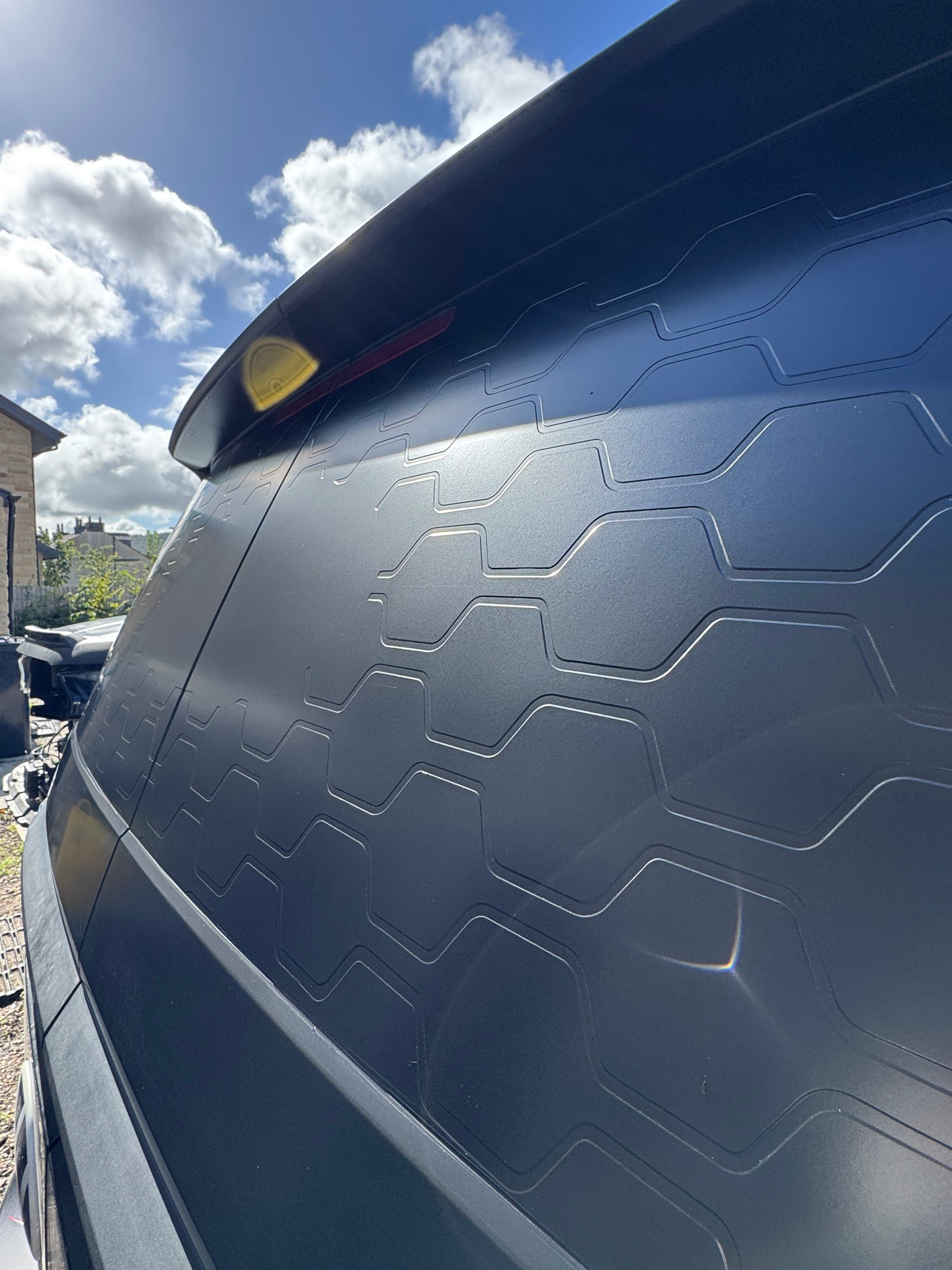 Close-up of a dark textured hexagonal-pattern vehicle wrap finish on a car roof/rear panel.